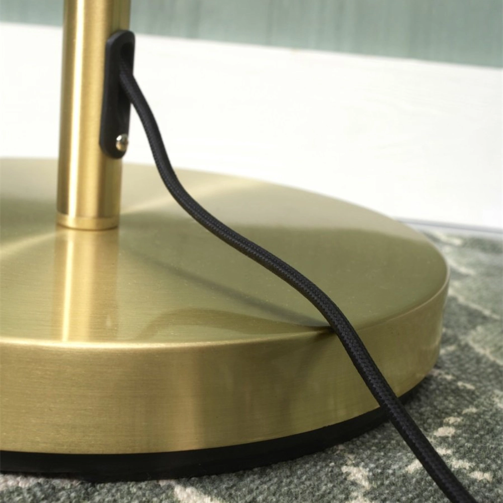 Candeeiro de Pé em Metal com Dois Focos Giratórios Bremen Base de metal dourado com cabo preto sobre tecido cinza