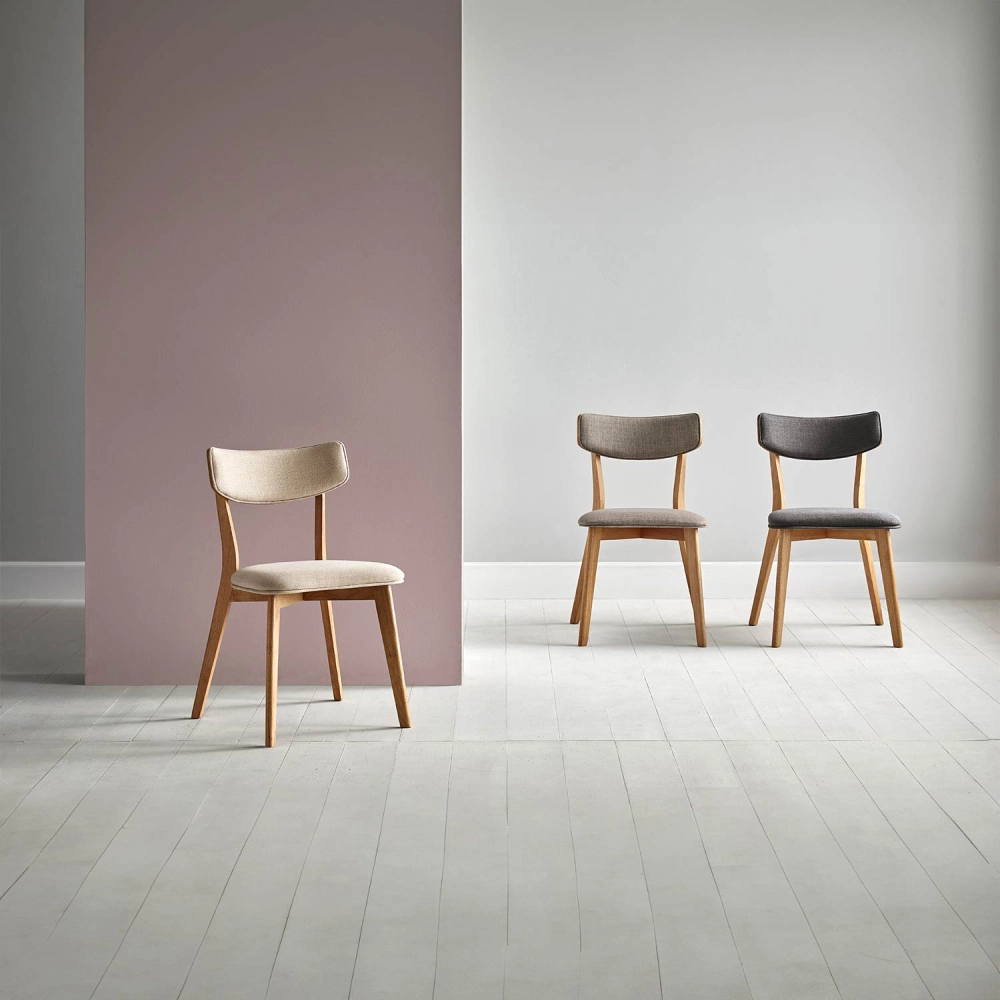 Cadeira estofada bege em carvalho Anais Três cadeiras com madeira clara e estofos em bege, cinza e preto, em fundo neutro com piso claro.