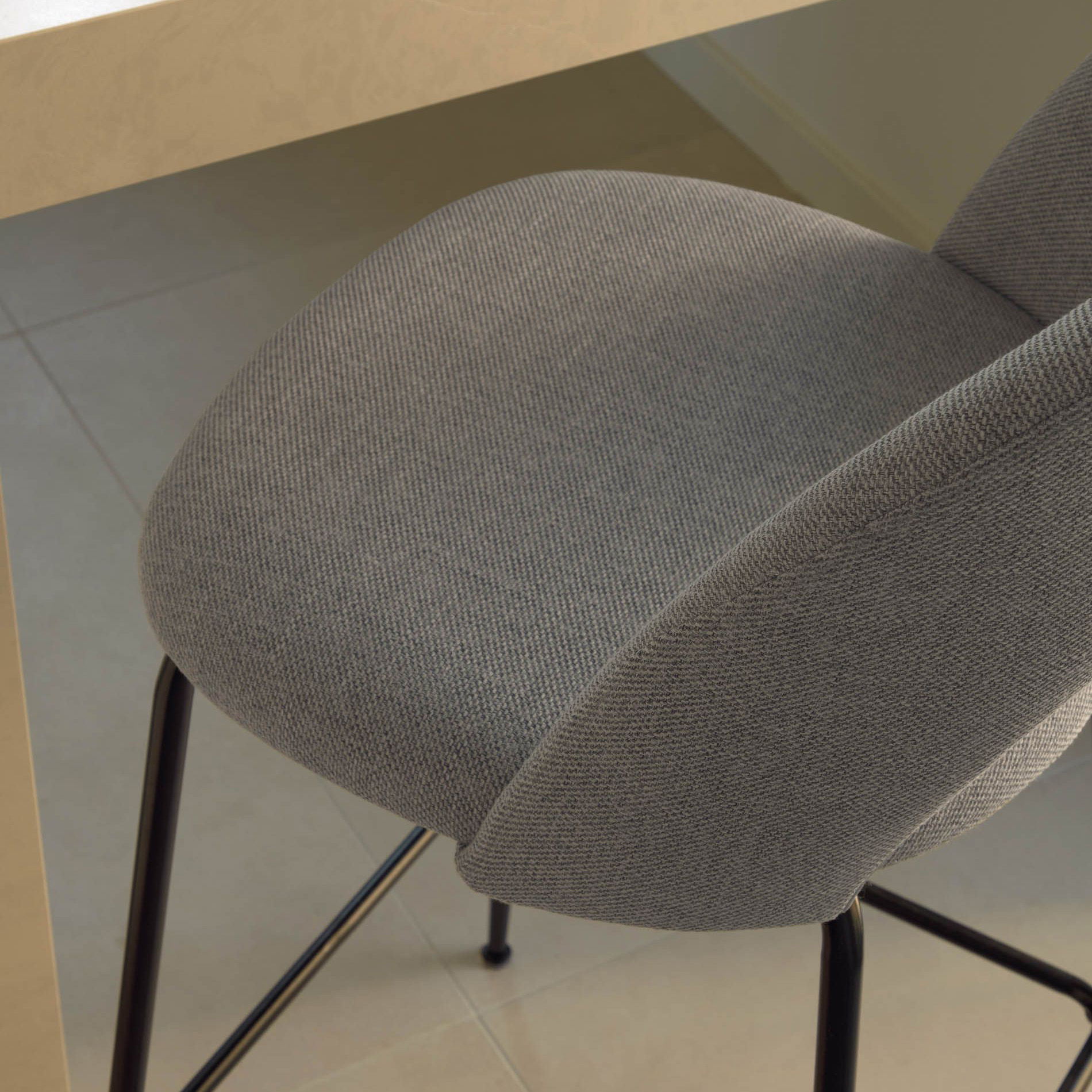 Cadeira alta Mahlia, estofada, 63cm Cadeira estofada cinzenta com pernas pretas junto a mesa de madeira