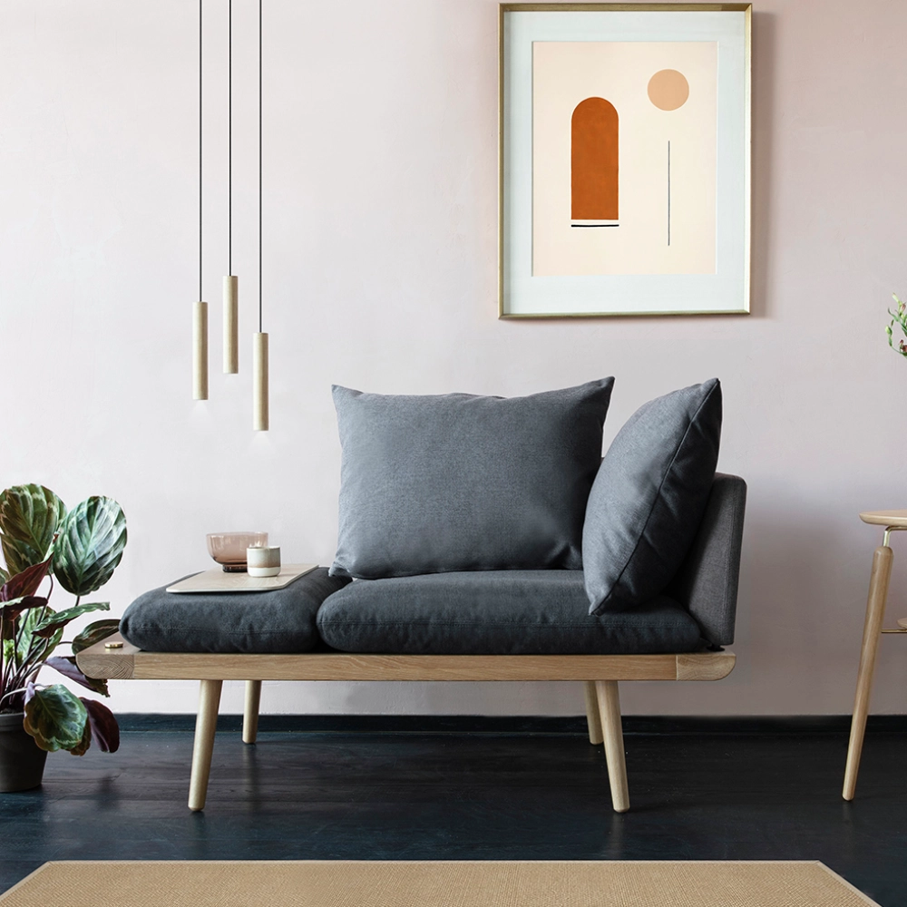 Candeeiro de Teto Chimes Cluster em Madeira de Carvalho Sofá cinza escuro em madeira clara numa sala com parede rosa, quadro abstrato e planta em vaso