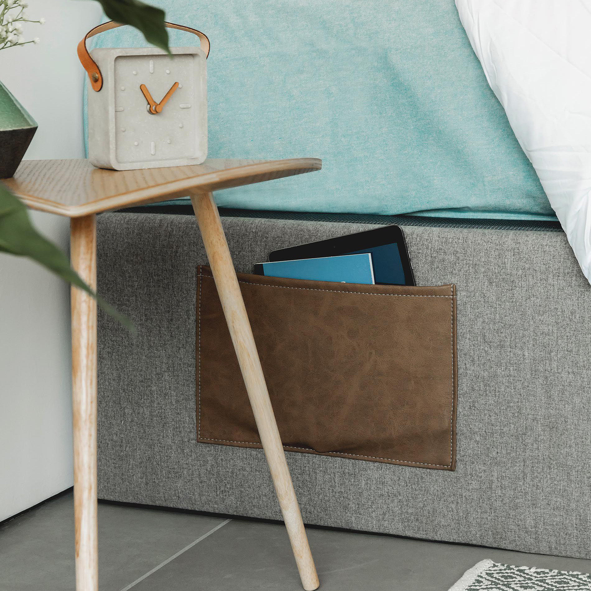 Sommier Matt, c/arrumação, 90x190 Mesa de cabeceira com relógio ao lado de cama com bolso castanho encaixado na roupa de cama cinzenta