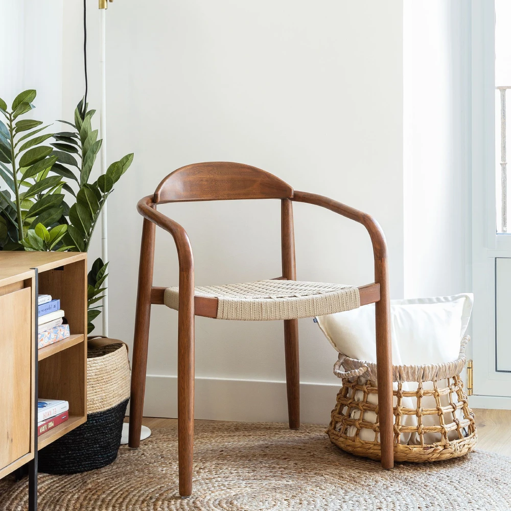 Cadeira com braços em nogueira e corda bege Mina Cadeira de madeira com assento em corda trançada num ambiente interior com decoração natural
