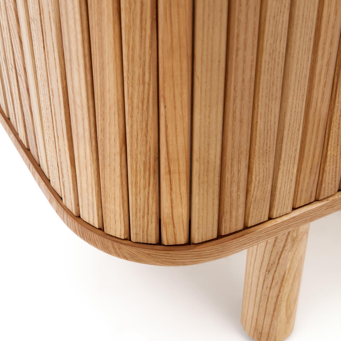 Aparador Malem, madeira de freixo, 110x160 Detalhe de móvel de madeira clara com lâminas verticais e pernas cilíndricas.