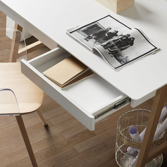 Secretária Dyna, madeira/lacado Secretária branca com gaveta aberta e cadeira de madeira clara junto ao chão de madeira