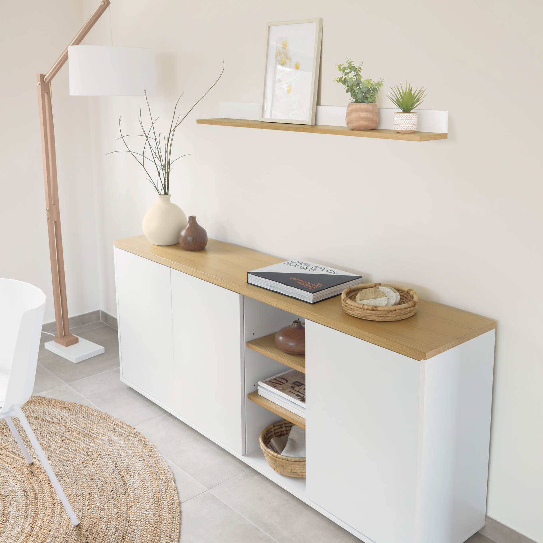 Aparador Abil, carvalho/lacado, 180x75 Móvel de armazenamento branco com tampo de madeira clara e decoração com vasos, livros, cesto, ao lado de lâmpada de pé e tapete redondo de fibras