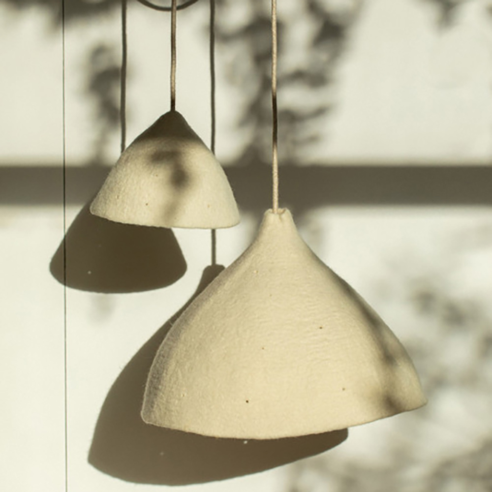 Candeeiro de Teto em Feltro Mármore Natural Tipi Ø22x16 Duas luminárias pendentes cónicas bege claro suspensas contra uma parede clara com sombras
