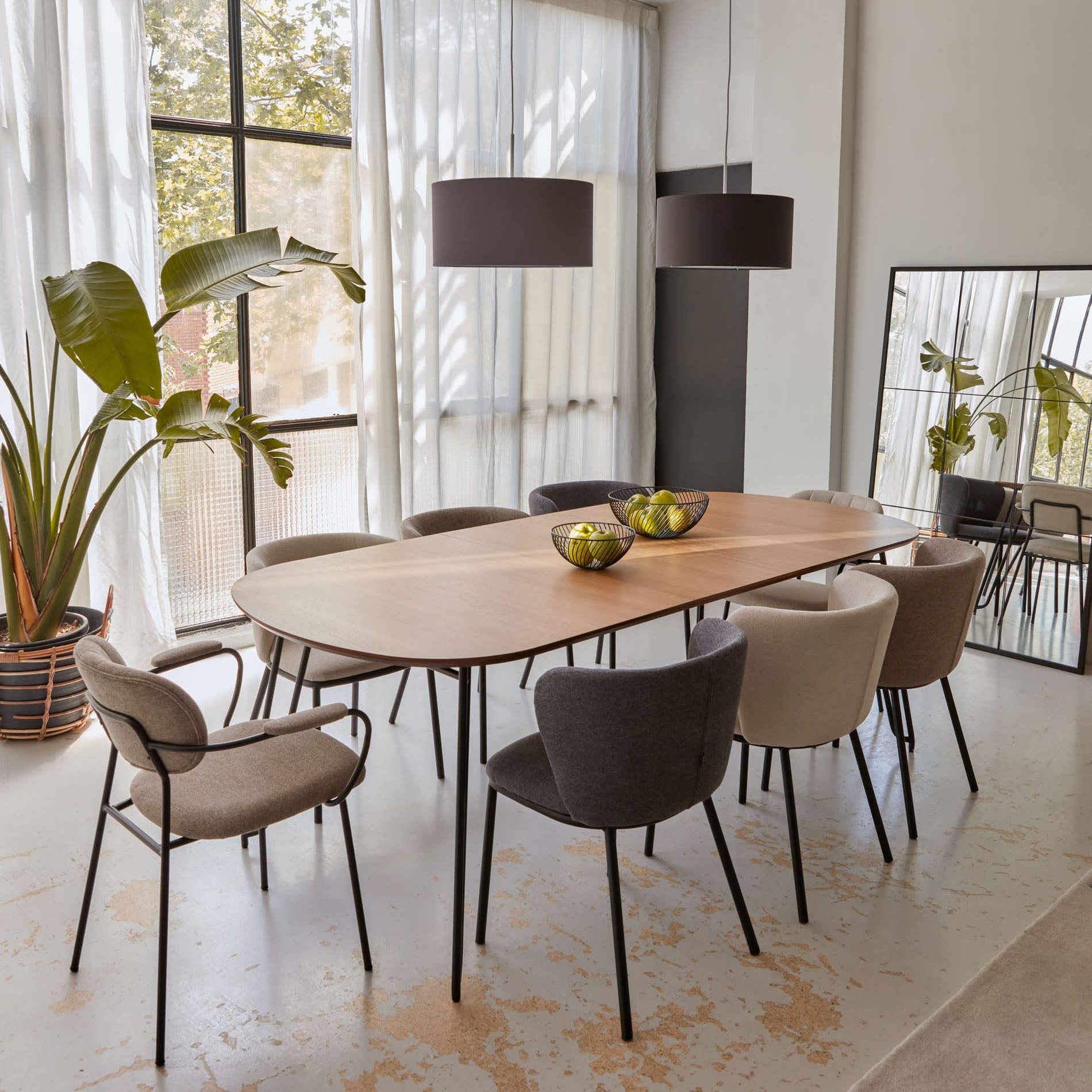Mesa extensível Novic, carvalho/metal, 170(320)x100 Mesa de jantar de madeira clara com oito cadeiras estofadas e luminárias pendentes pretas, espelho e planta em ambiente moderno
