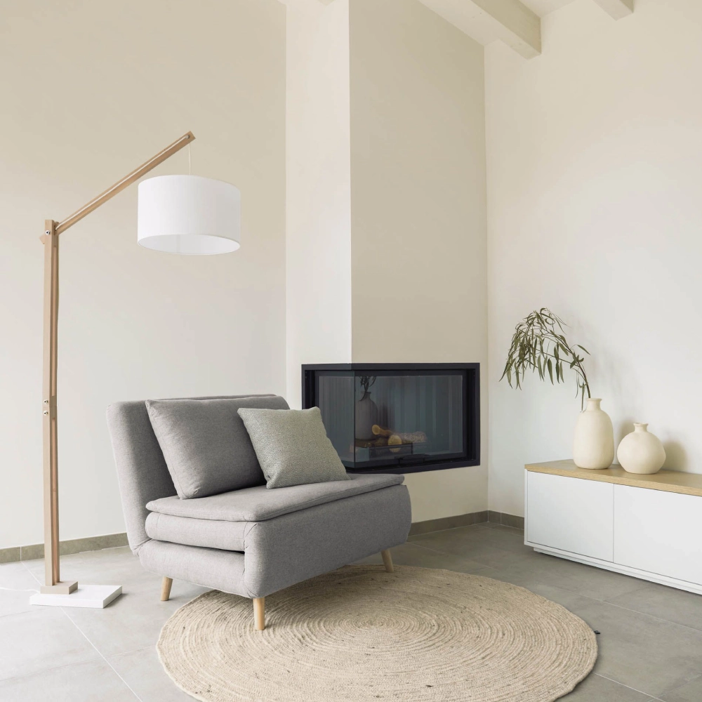 Candeeiro de Pé em Madeira Branco Zizar Cadeira cinzenta, luminária de chão, lareira embutida, tapete redondo e móvel branco com vasos