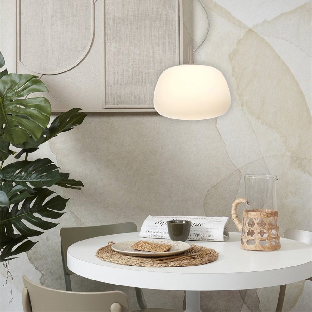 Candeeiro de Teto em Vidro Branco Sapporo Mesa redonda branca com decoração simples e planta verde numa sala clara.