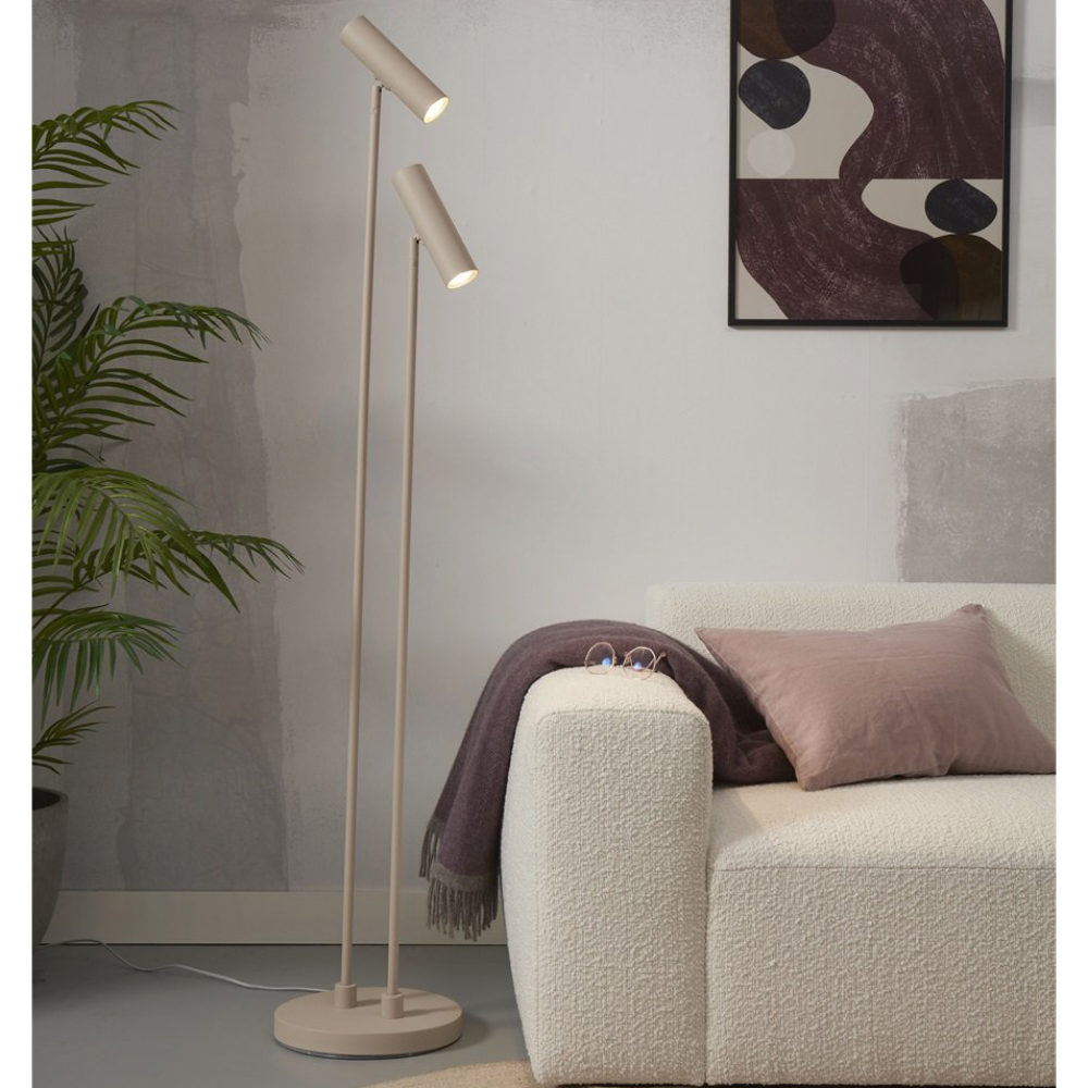 Candeeiro de Pé Havana com Duplo Foco Candeeiro de pé moderno em madeira clara ao lado de sofá creme com almofadas e manta rosa e roxa
