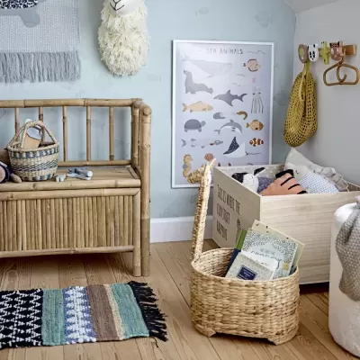 Quarto infantil com móveis de bambu, cestos de vime, tapete colorido e poster de animais marinhos