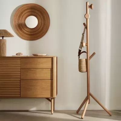 Móvel de madeira com gavetas, espelho redondo de palha e cabideiro de madeira com bolsa, ambiente minimalista