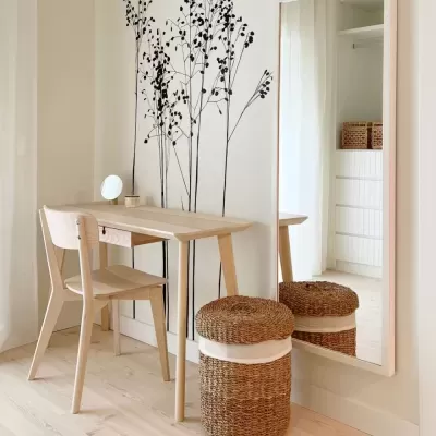 Mesa e cadeira de madeira clara com cesto de vime e espelho grande