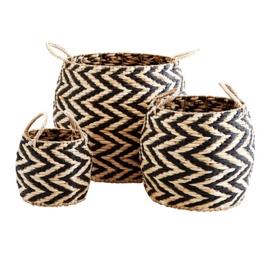 Três cestos de palha com padrão zig-zag preto e natural, com alças, sobre fundo branco