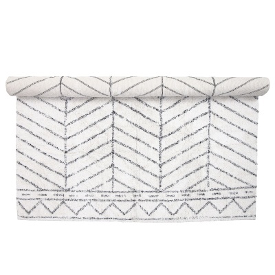 Tapete branco com padrão geométrico cinza escuro parcialmente enrolado