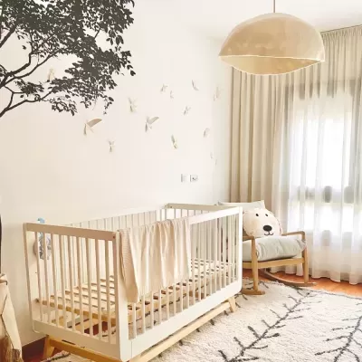 Quarto infantil com berço de madeira clara e cadeira com almofada de cachorro