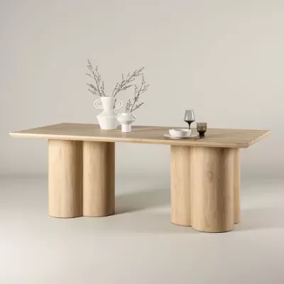 Mesa de jantar em madeira clara com jarros brancos e copos de vidro