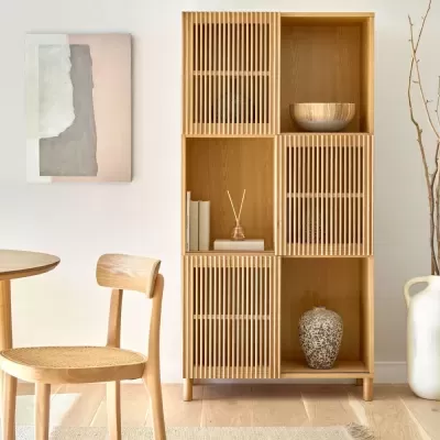 Móvel de madeira clara com portas de ripas e decoração em ambiente minimalista