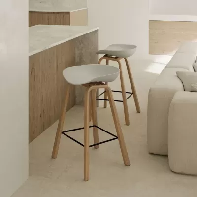 Bancos altos cinza claro com pernas de madeira junto a balcão de cozinha