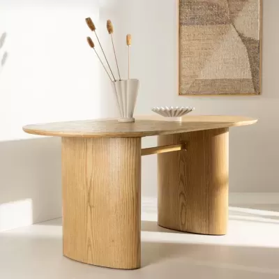 Mesa de madeira clara com vaso e recipiente decorativo numa sala clara com quadro abstrato