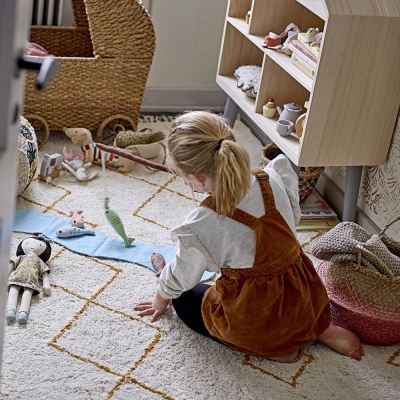 Criança a brincar no chão com brinquedos e tapete decorado em quarto infantil