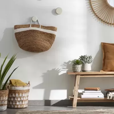 Cesta de palha pendurada e decoração interior com banco de madeira, plantas e espelho redondo