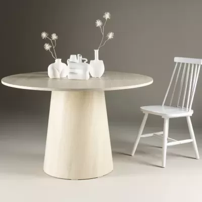 Mesa redonda de madeira clara com cadeira branca e jarros brancos com flores secas