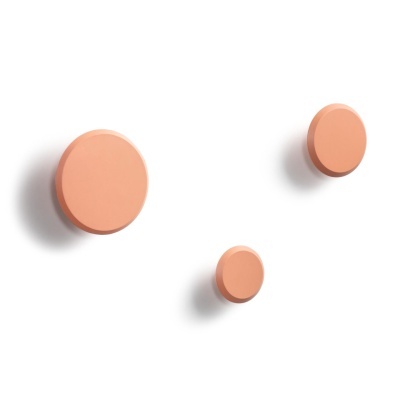 Três ganchos circulares terracota numa parede branca