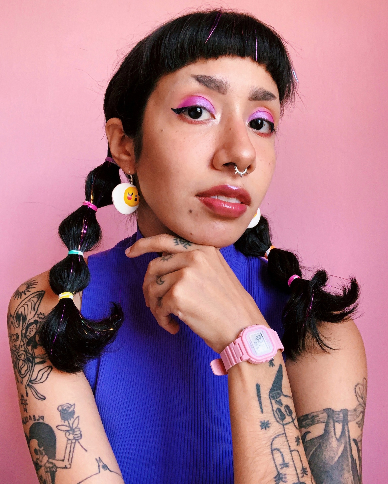 Relógio digital rosa no pulso de mulher com cabelo apanhado e brincos redondos.