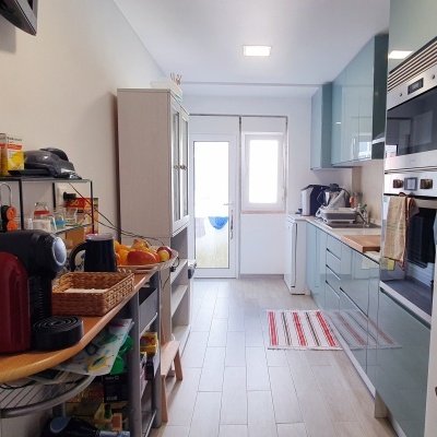 Cozinha moderna com armários azuis, eletrodomésticos e frigorífico branco decorado.