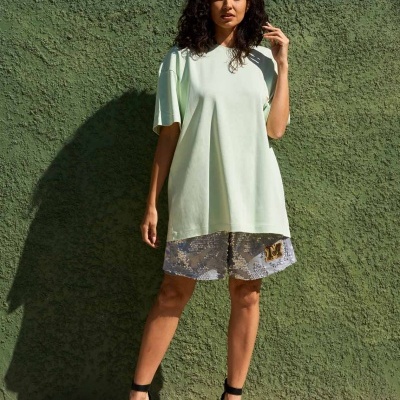 Vestido casual verde claro com renda cinza e sapatos pretos em fundo verde texturado