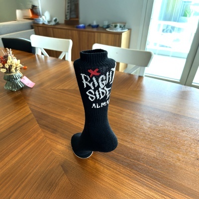 Meia preta de malha com texto branco e vermelho numa mesa de madeira