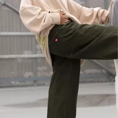 Calças cargo verde-escuro com casaco creme oversized em ambiente urbano