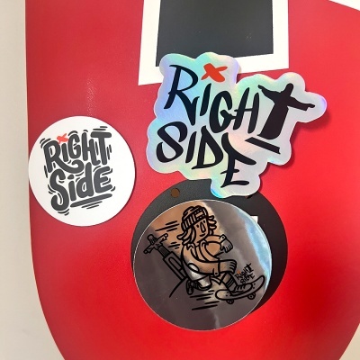 Três autocolantes com texto e ilustração numa superfície vermelha