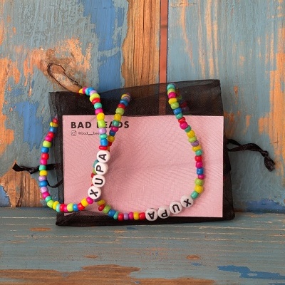 Colar e pulseira coloridos com bolas de plástico e letras formando 'XUPA'