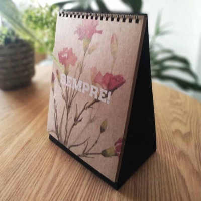 Calendário de mesa com capa floral e texto 'SEMPRE!' em papel reciclado.