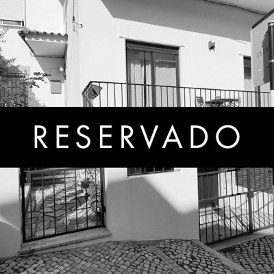 Casa branca com porta metálica preta e palavra RESERVADO sobreposta