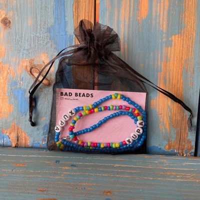 Colar colorido com letras em bolsa preta de organza sobre madeira azul