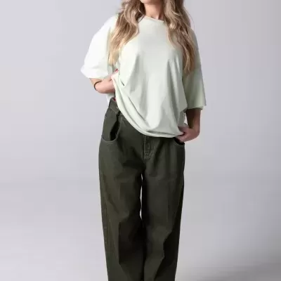 Mulher com t-shirt verde claro e calças verdes escuras em fundo branco