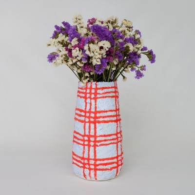 Vaso cerâmico branco com padrão laranja e flores secas roxas, brancas e rosas.