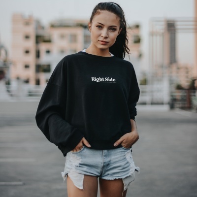 Mulher com sweatshirt preta 'Right Side' e calções de ganga azul claro num ambiente urbano