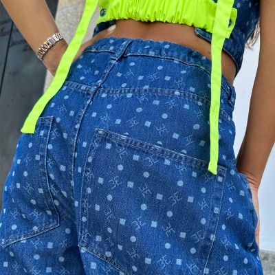 Calças de ganga azuis padrão com top amarelo fluorescente e pulseira metálica