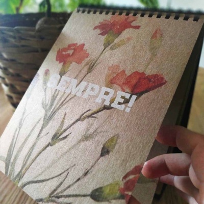 Caderno espiral com capa de flores vermelhas e texto SEMPRE!