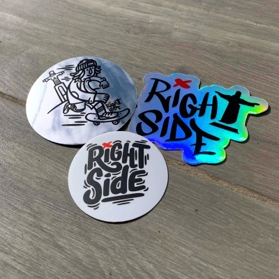 Três autocolantes variados com texto 'Right Side' e desenho de personagem a andar de skate sobre madeira cinzenta