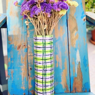 Vaso xadrez com flores secas em cadeira azul desgastada