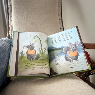 Livro infantil aberto com ilustrações coloridas de animal cinzento numa cadeira clara