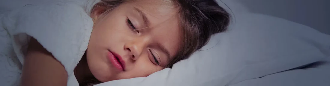 Criança a dormir numa cama com lençóis brancos