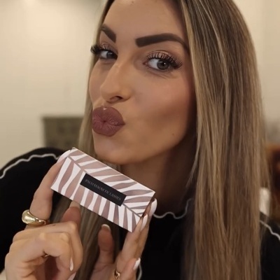 Mulher loira segurando caixa zebrada com texto RIBAGENCY INFINITY