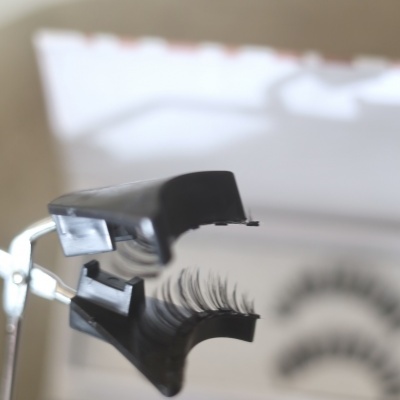 Esmirrador de pestanas metálico com pestanas postiças e tubo rosa no fundo