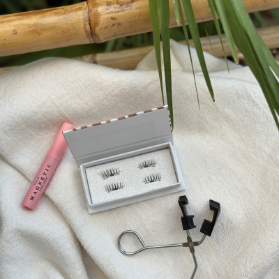 Conjunto de pestanas magnéticas com aplicador e embalagem sobre tecido branco e decoração natural